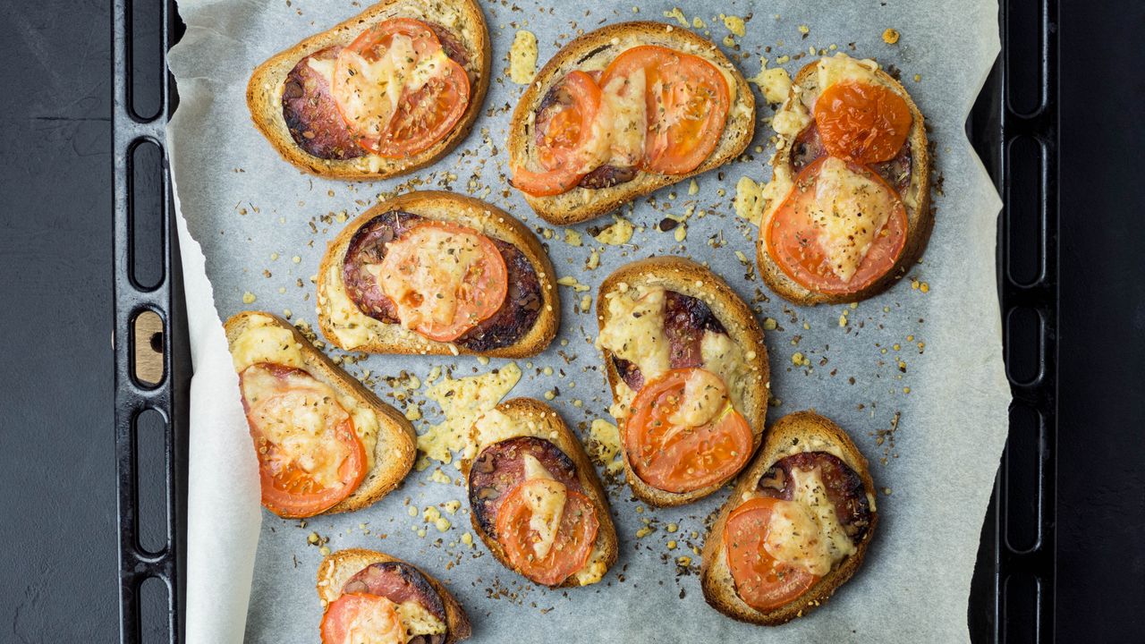 Freshly baked tomato and cheese toasts on a baking tray, perfect snack idea.