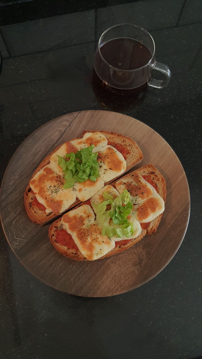 Delicious cheese and tomato toasts with fresh garnish served with a glass of coffee.